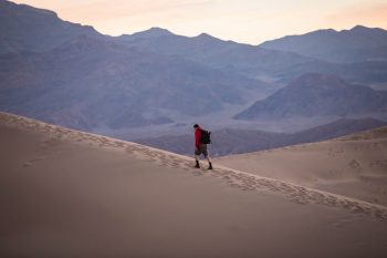 person in red hoodie walking on desert